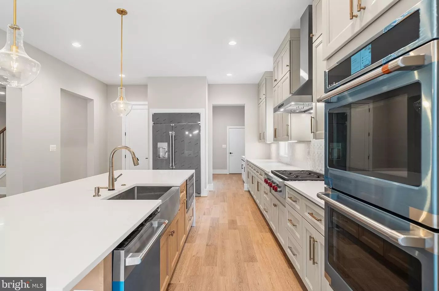 Kitchen island with brass fixtures, pendant lighting and stainless appliances