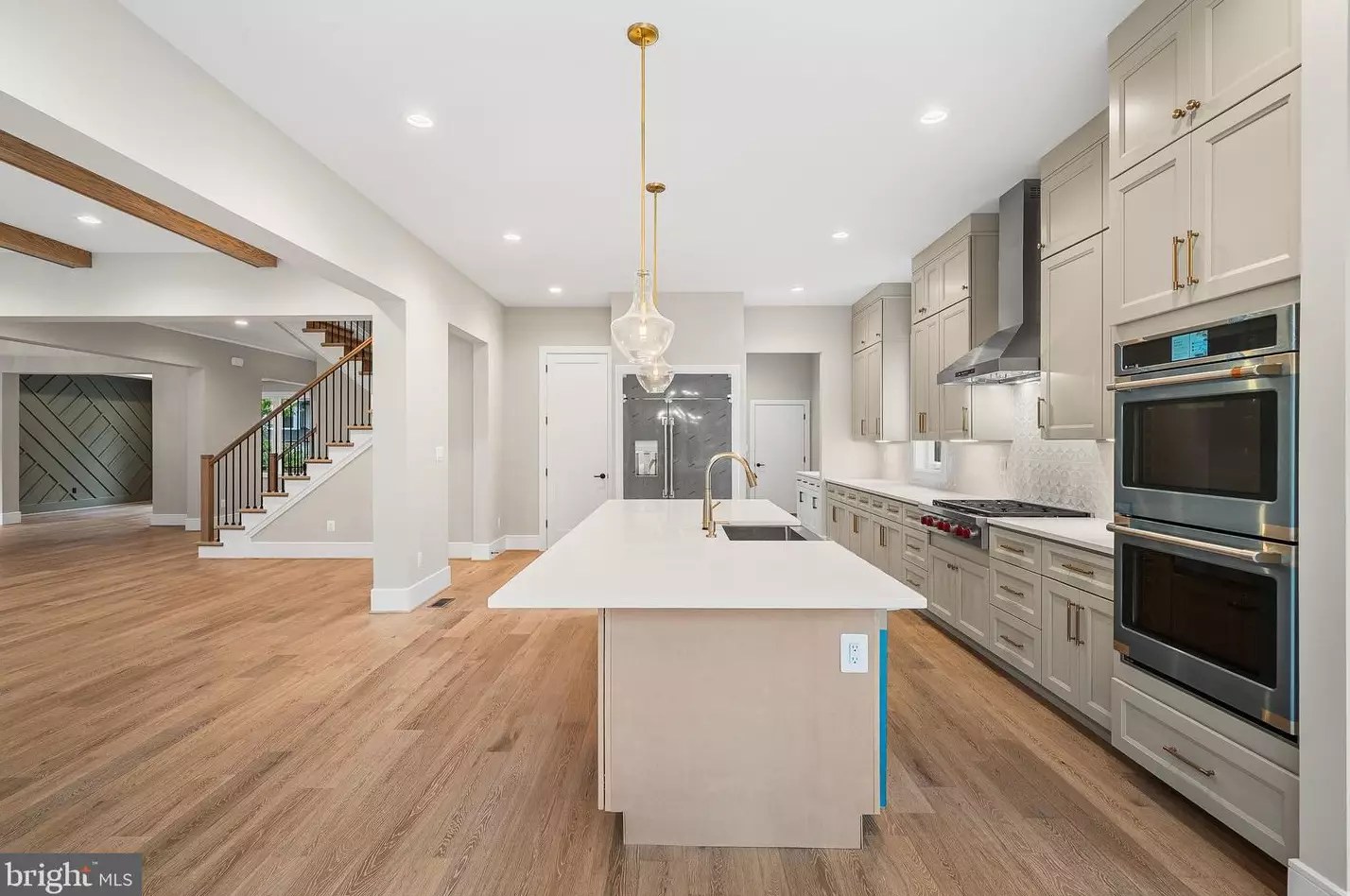 Open kitchen with large quartz island, wall ovens and gas cooktop