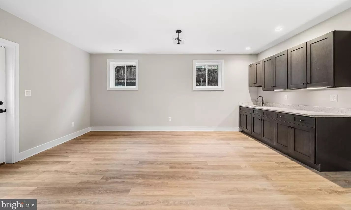 Lower-level wet bar with dark cabinetry and stone countertop